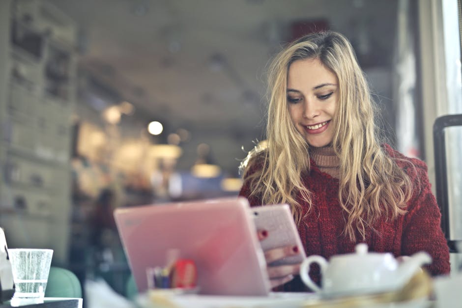 A young woman engaged with a tablet in a warm, inviting café atmosphere.